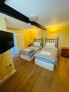 two beds in a room with a flat screen tv at The Boat Inn Hayton in Retford