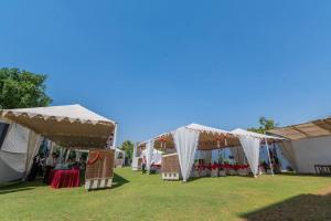a row of tents with tables and chairs in a field at Hotel Prime Safari in Jaipur
