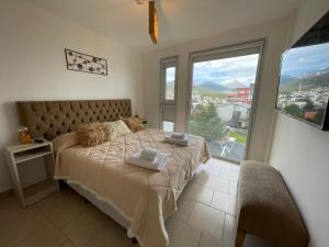 a bedroom with a bed with a large window at Infinity View 3-4 in Ushuaia