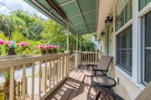 une terrasse couverte avec 2 chaises et un balcon fleuri dans l'établissement Weeden Cottage, à Saint Augustine