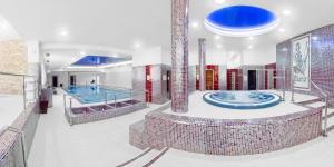 a bathroom with two hot tubs and a swimming pool at Spa Hotel Diana in Františkovy Lázně