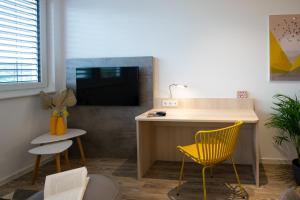 ein Wohnzimmer mit einem Schreibtisch und einem gelben Stuhl in der Unterkunft Livin63 Studio Apartments in Hösbach