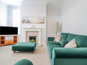 a living room with a green couch and a fireplace at 24 Cadnant Park in Conwy