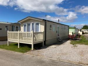 a tiny house with a porch and a deck at Adams Caravan Holidays in Morecambe