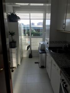 a kitchen with white cabinets and a large window at Apartamento Conchita in Vigo