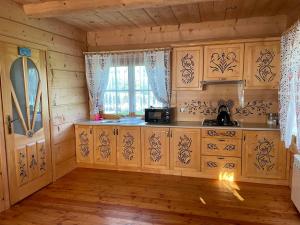 a kitchen with wooden cabinets and a window at Domek u Orszulaków in Witów