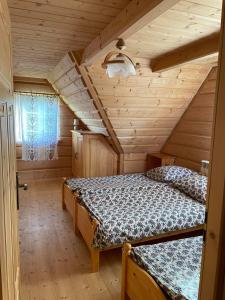 a bedroom with two beds in a log cabin at Domek u Orszulaków in Witów