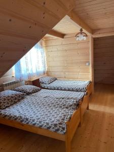 a bedroom with two beds in a wooden house at Domek u Orszulaków in Witów