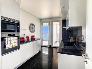 eine Küche mit weißen Schränken und einer großen Uhr an der Wand in der Unterkunft The Best Sea View Apartment by LovelyStay in Funchal + 23 Fotos