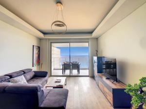 ein Wohnzimmer mit einem Sofa, einem TV und einem Tisch in der Unterkunft The Best Sea View Apartment by LovelyStay in Funchal