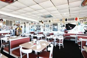 a restaurant with white tables and red chairs at Olympic Island Beach Resort in Wildwood Crest