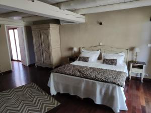 a bedroom with a large white bed and a dresser at Le Chant du Coeur in Roussillon