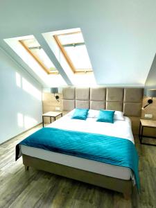 a bedroom with a bed with blue sheets and skylights at Pokoje gościnne - Kasztelańska 8 in Stara Kamienica