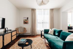 Redland Suites - Apartment 5 في بريستول: غرفة معيشة مع أريكة خضراء وتلفزيون