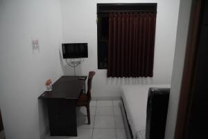 Habitación pequeña con escritorio y TV. en Casa Feby Guest House, en Bandung