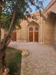 a large brick building with two doors and a tree at Marhaba boutique Madrasah 15th-16th century in Bukhara