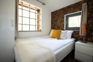 a bedroom with a white bed with a wall at Pokoje przy Plaży Dźwirzyno -Pelikan Resort in Dźwirzyno