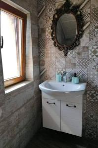 La salle de bains est pourvue d'un lavabo, d'un miroir et d'une fenêtre. dans l'établissement River Hills Guest House, à Lesichevo