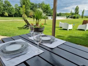 a wooden table with plates and wine glasses on it at Gites de Cognac in Bréville