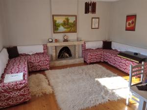 a living room with red couches and a fireplace at Meti Guest House in Krujë