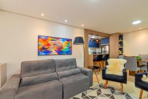 a living room with a couch and a painting on the wall at 1 quadra da Catedral e 2 vagas de garagem in Canela