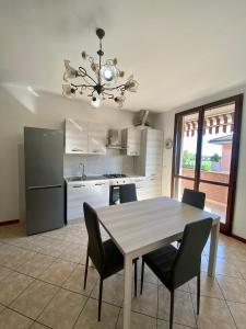 cocina con mesa, sillas y nevera en Appartamento la Pioppa con posto auto e Wi-Fi en Castelfranco Emilia