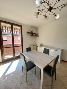mesa de comedor con sillas y lámpara de araña en Appartamento la Pioppa con posto auto e Wi-Fi en Castelfranco Emilia