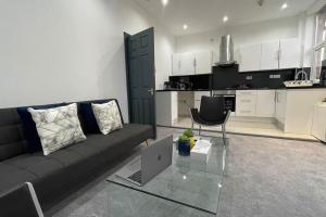 uma sala de estar com um sofá e um computador portátil numa mesa de vidro em Suite 1- Luxury 1 Bed Apt- Leicester City- Free Parking em Leicester