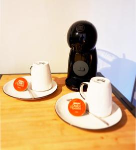 two cups on plates next to a coffee maker at Suite Oasis en Provence Luberon Pierrevert in Pierrevert