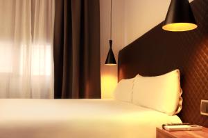 um quarto com uma cama branca e uma janela em Woohoo Suites Madrid em Madri