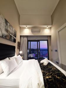 a bedroom with a large white bed with a large window at Top Floor Penthouse - Overlooking Times Square Casino in Pretoria