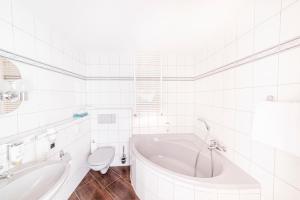 a white bathroom with a tub and a toilet at Hotel Forstmeister in Schönheide +44 photos