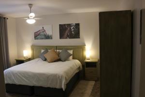 Livivane Guest House في Simunye: غرفة نوم مع سرير مع مواقف ليلتين ومصباحين