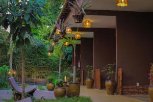 un hall avec des plantes en pot et des lustres dans l'établissement Muda Hotel, à Tianguá