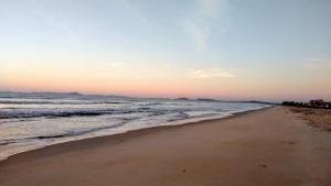 plaża o zachodzie słońca z oceanem w obiekcie Apartamento à beira mar Praia de Unamar w mieście Cabo Frio