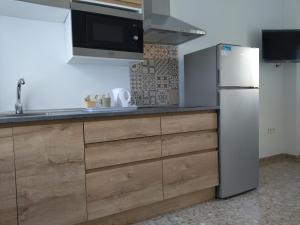 a kitchen with wooden cabinets and a refrigerator at Alojamiento -Estudio Centro Dos Hermanas in Dos Hermanas