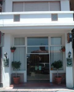 un bâtiment blanc avec des plantes en pot devant lui dans l'établissement Costa Azzurra, à Giardini Naxos