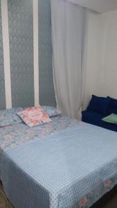 a bedroom with a bed with a blue bedspread and a curtain at Apartamento à beira mar Praia de Unamar in Cabo Frio