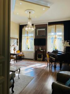 een woonkamer met een piano en een kroonluchter bij Logod Panorama Apartman in Boedapest