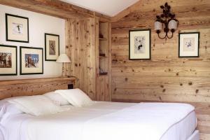 Auberge de La Maison في كورمايور: غرفة نوم بسرير ابيض وجدران خشبية