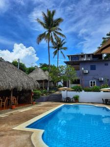 una piscina en un complejo con palmeras y un edificio en Hotel Tunco Lodge en La Libertad