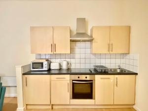 a kitchen with wooden cabinets and a microwave at Elmcroft Apartments Halifax City Centre in Halifax