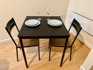 a black table with two glasses and two chairs at Elmcroft Apartments Halifax City Centre in Halifax