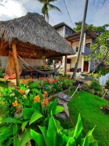 einen Garten mit einer strohgedeckten Hütte und ein paar Blumen in der Unterkunft Hotel Tunco Lodge in La Libertad