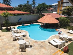 a pool with a table and chairs and a umbrella at Suites Bouganville ( casa 2) in Porto De Galinhas