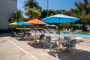 San Clemente Inn في سان كليمنت: مجموعة طاولات وكراسي مع مظلات بجانب المسبح