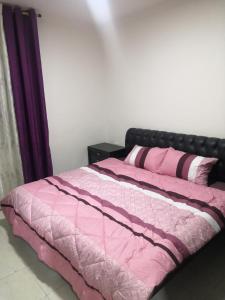 a bed with a pink comforter and two pillows at Al-Shokhaibie 51 Building- Soufan Studios in Ţāb Kirā‘