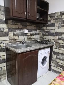 a kitchen with a sink and a washing machine at Al-Shokhaibie 51 Building- Soufan Studios in Ţāb Kirā‘