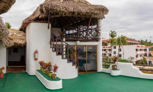 a villa with a thatched roof and a green floor at Hotel Bungalows Acuario in Puerto Escondido