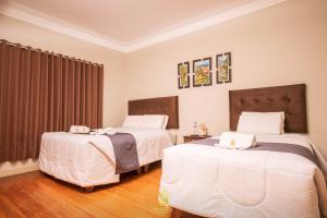 1 dormitorio con 2 camas con sábanas blancas en Hostal Virreinal AQP, en Arequipa